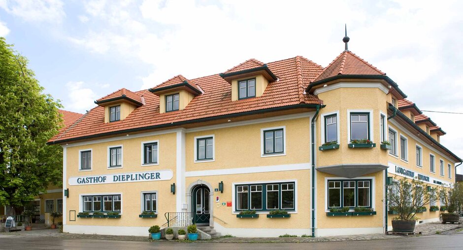 Außenansicht des Gasthofs in traditionellem Baustil mit gelber Fassade und grünen Fensterrahmen