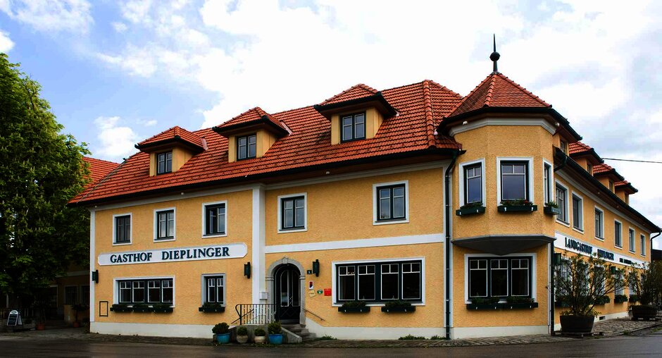 Außenansicht des Gasthofs in traditionellem Baustil mit gelber Fassade und grünen Fensterrahmen