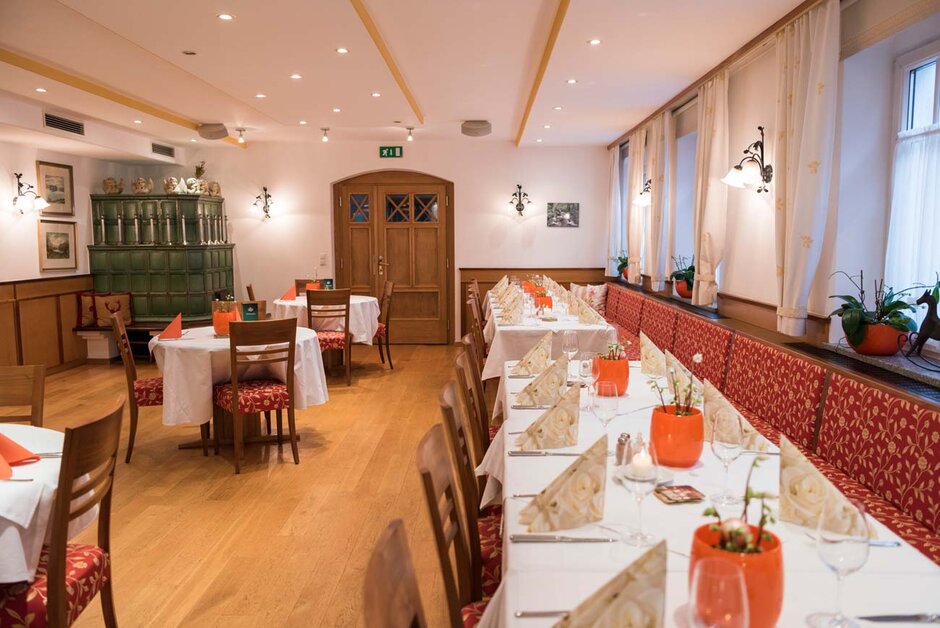 Stüberl mit gedeckten Tischen, Kamin, eingeschalteter Beleuchtung