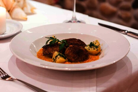 Knödel und Kartoffel in einem Suppenteller, auf Sauce angerichtet