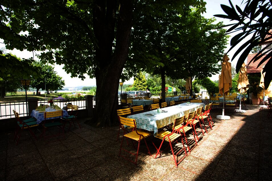Schattiger Gastgarten mit Tischen unter Kastanienbäumen