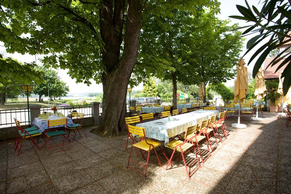Schattiger Gastgarten mit Tischen unter Kastanienbäumen